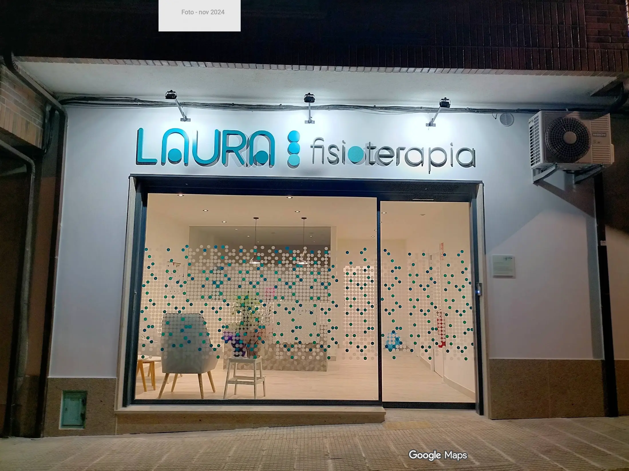 Fachada de la clínica con el rótulo «Laura fisioterapia» iluminado sobre un gran escaparate decorado con círculos turquesa